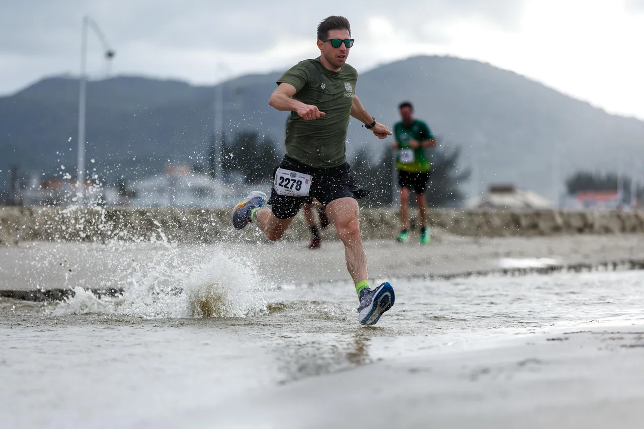 Corredor atravessando a água na Meia Maratona Guarda do Embaú de 2026