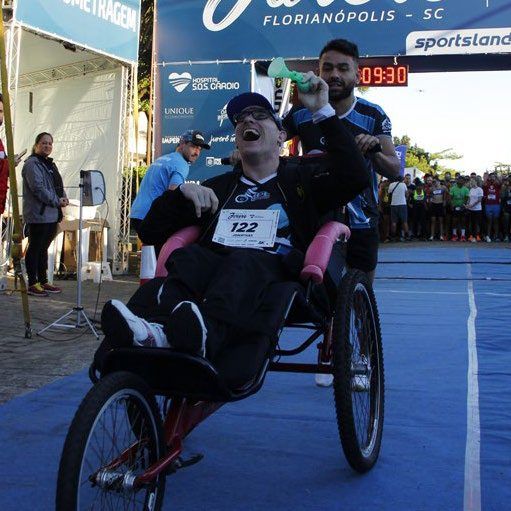 Atleta cadeirante participando de prova com apoio
