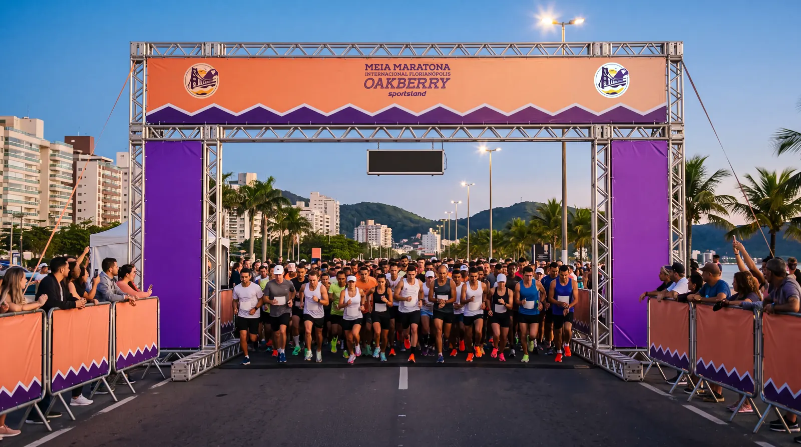 Largada bajo el pórtico de la Meia Maratona Internacional de Florianópolis Oakberry al amanecer, con el público en las vallas