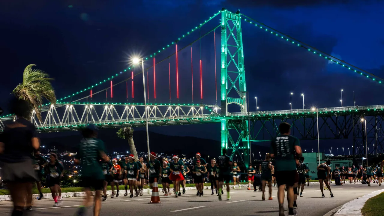 Corredores en la Beira-Mar Continental con la Ponte Hercílio Luz iluminada, en la edición 2025